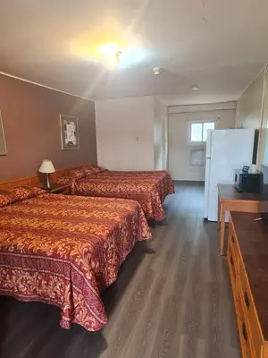 a hotel room with two beds and a refrigerator at Skyways Motel in Gravenhurst