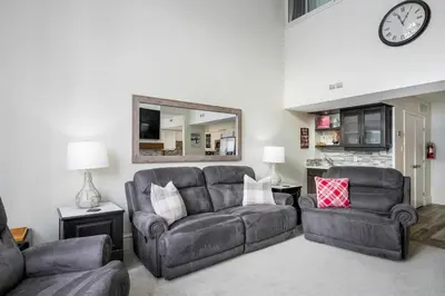 a living room with a couch and a chair and a clock at Slopeside Haven - Ski-In Ski-Out Adventure Base in Blue Mountains