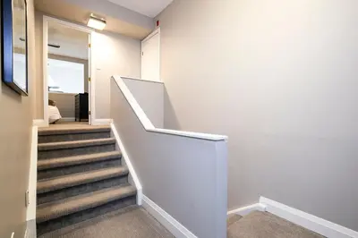 a hallway with a staircase with a white stair railing at Hillside Lookout - Ski-In Ski-Out Alpine Escape in Blue Mountains