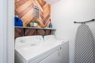 a laundry room with a washer and a wooden wall at Large 4 Br - 5 Bathroom with Heated Pool 2 King beds Sauna Pool Table in Blue Mountains