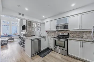 a kitchen with white cabinets and stainless steel appliances at Slopeside Hideout Ski-In Ski-Out Walk to Village in Blue Mountains