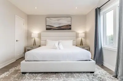 a white bedroom with a white bed and two windows at Modern Luxury Townhome Walk to Blue Shuttle in Blue Mountains