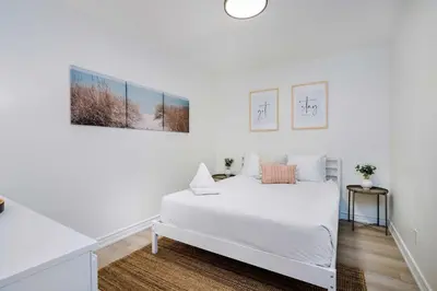 a white bedroom with a white bed and two pictures on the wall at Cranberry Apres Nest Bright Reno Near Blue Mtn in Collingwood