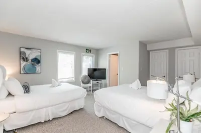 a white room with two beds and a television at The Nest - Walk to Blue Private Patio in Blue Mountains