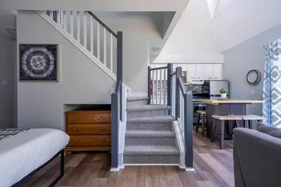 a staircase in a room with a bed and a kitchen at Wanderer Way Loft Ski-In Ski-Out - Pool & Hot Tub in Blue Mountains