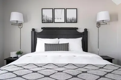 a bedroom with a black and white bed with two lamps at Stay A While Ski-In-Out Hot Tub & Shuttle in Blue Mountains