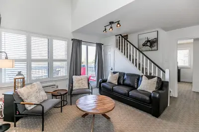 a living room with a black leather couch and chairs at Mountain Peaks Ski-In-Out Pool Shuttle in Blue Mountains