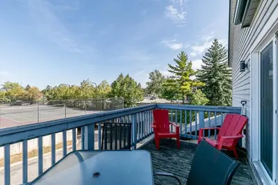 a balcony with two red chairs and a tennis court at Mountain Peaks Ski-In-Out Pool Shuttle in Blue Mountains