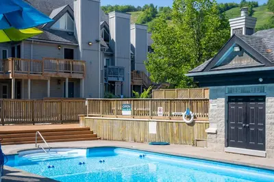 a swimming pool with a wooden fence and a house at Fox Ridge - Ski-In-Out Pool Hot Tub Shuttle in Blue Mountains