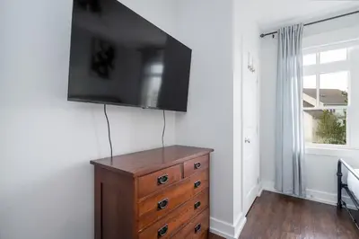 a wooden dresser with a television on a wall at The Blue - Walk to the Village Shuttle & Hot Tub in Blue Mountains