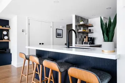 a kitchen with a white counter and stools at View to Blue - Walk to the Village Mountain Views in Blue Mountains