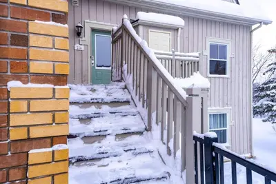 a snow covered stairway to a house with a green door at Snowy Mountain Summit & Sol - Shuttle - Patio in Blue Mountains