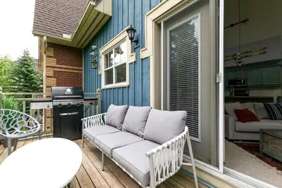 a white couch sitting on a porch with a grill at Lookout Lodge - Private Patio - Shuttle to Blue in Blue Mountains