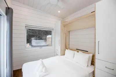 a bedroom with a white bed and a window at The Hideaway - Tiny House in Flesherton