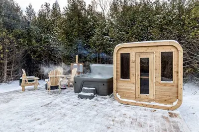 a small wooden cabin with a grill in the snow at The Hideaway - Tiny House in Flesherton