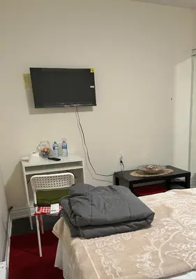 a bedroom with a bed and a desk with a tv on the wall at V-Swim Suite-2 in Toronto