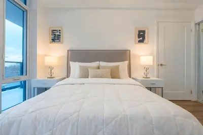 a bedroom with a large white bed with two lamps at RivetStays - The Westmounts in Toronto