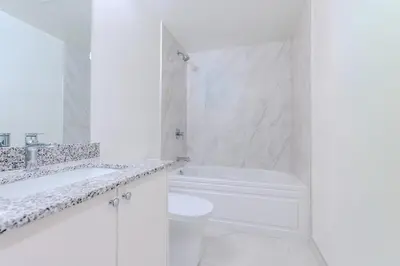 a white bathroom with a tub and a sink and a toilet at RivetStays - The Westmounts in Toronto