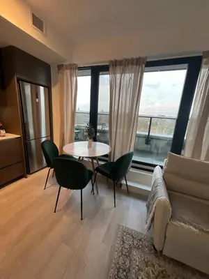 a living room with a table and chairs and a large window at Serene Cozy 1BDRM Condo near Sherway Mall, Lakeshore, & Airport in Toronto