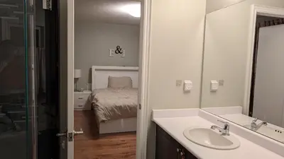 a bathroom with a sink and a bedroom with a bed at Bright ensuite with WiFi Parking available in Markham