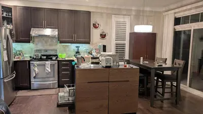 a kitchen with wooden cabinets and a table in it at Bright Bedroom with Shared bathroom and WiFi Parking available in Markham