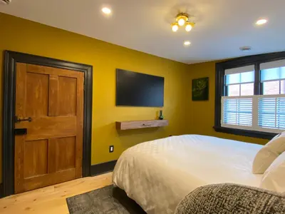 a bedroom with a bed and a flat screen tv at Hattan House Boutique Hotel Bed & Breakfast in Niagara on the Lake