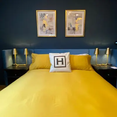 a yellow bed in a blue room with two lamps at Hattan House Boutique Hotel Bed & Breakfast in Niagara on the Lake