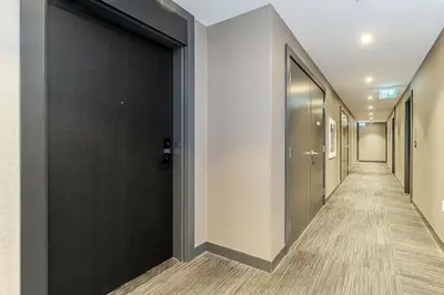 a corridor of a hallway with black doors and wooden floors at 1 BR Boutique Charm, Urban Calm! in Oakville