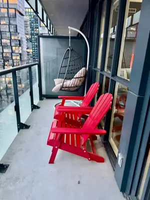 two red chairs on a balcony with a swing at CN Tower and Rogers Centre View and Central Island Lake View in Toronto