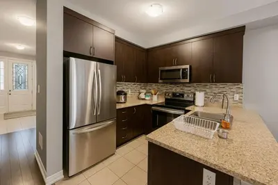 a kitchen with a stainless steel refrigerator and wooden cabinets at Cozy 3 Bed Whole Rental Home for your stay! in Brampton