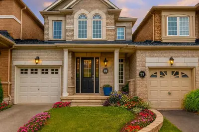 a house with two garage doors and flowers at Cozy 3 Bed Whole Rental Home for your stay! in Brampton