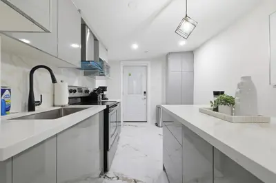 a white kitchen with a sink and a counter at Modern Queen West Retreat Massive Patio 65 TV in Toronto