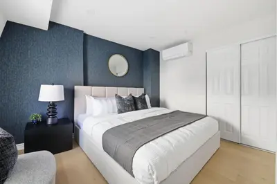 a bedroom with a large bed and a chair at Modern Queen West Retreat Massive Patio 65 TV in Toronto