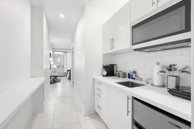 a white kitchen with white cabinets and a sink at Stylish 2BR Retreat by Queen West in Toronto