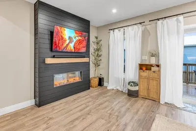 a living room with a fireplace and a tv on a wall at Cozy & Modern Home | EV Charger in Elmira