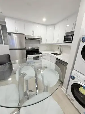 a kitchen with a glass table and white cabinets at Modern and Cozy Basement Suite,2 Bedrooms with Kitchen ,Parking and Separate Entrance in Milton