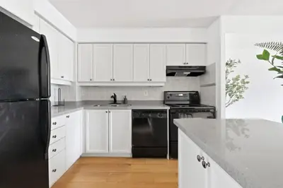 a kitchen with white cabinets and a black refrigerator at Tropical Designer King Suite - Sleeps 5 - Parking in Mississauga