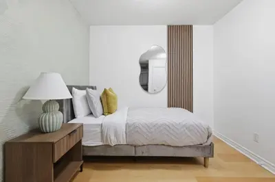 a bedroom with a bed and a table with a lamp at Tropical Designer King Suite - Sleeps 5 - Parking in Mississauga