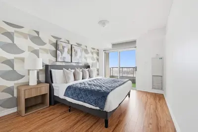 a bedroom with a bed and a large window at Elegant 2BR Sky Condo for 9 - Terrace - Lake Views in Mississauga