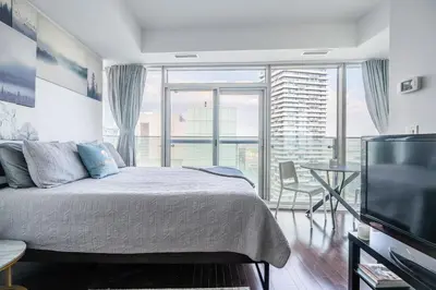 a bedroom with a bed and a flat screen tv at Lake view Studio Condo High Floor Downtown Toronto in Toronto