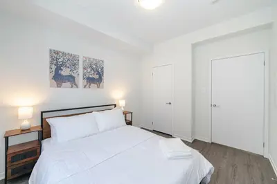 a white bedroom with a bed and two lamps at Centrally Located 3-Bedroom Townhouse in Vaughan in Vaughan