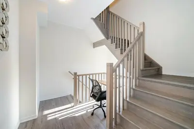 a staircase with a chair in a room with white walls at Centrally Located 3-Bedroom Townhouse in Vaughan in Vaughan