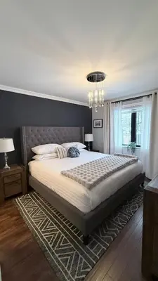 a bedroom with a large bed and a chandelier at Beautiful Home with Hot tub by YYZ, 20min to CN Tower in Toronto
