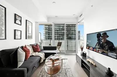 a living room with a couch and a flat screen tv at Chic Downtown Retreat with Private Patio in Toronto