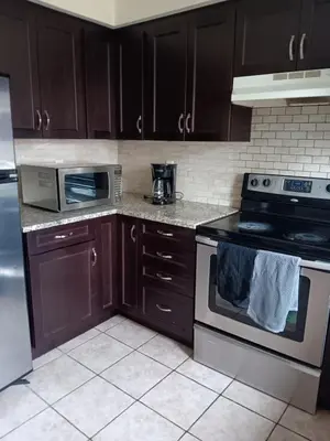 a kitchen with brown cabinets and a stove top oven at House near Toronto Pearson Airport in Brampton
