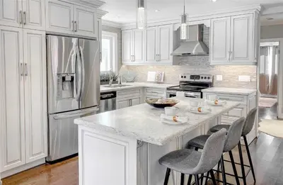 a kitchen with white cabinets and a island with bar stools at Beautiful 3 bed 2 bathroom home Toronto in Toronto