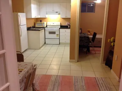 a kitchen with white appliances and a table in it at Maria's Homestay in Thornhill