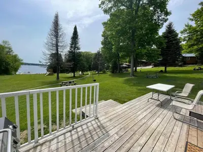 a wooden deck with a table and chairs and a park at #90 Lakefront 3-bdrm Chalet in Muskoka in Port Carling