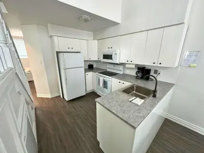 a kitchen with white cabinets and a white refrigerator at Family Townhome with outdoor pool access in Collingwood