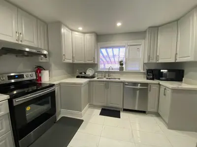 a kitchen with white cabinets and black appliances at Adorable 3 private rooms- main with free parking in Toronto